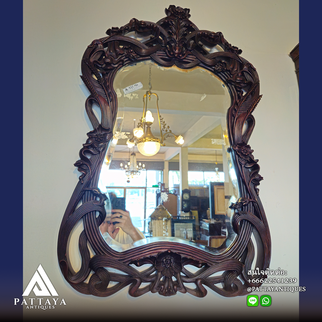 A pair of heavily carved mahogany Art Nouveau bevelled edged mirrors