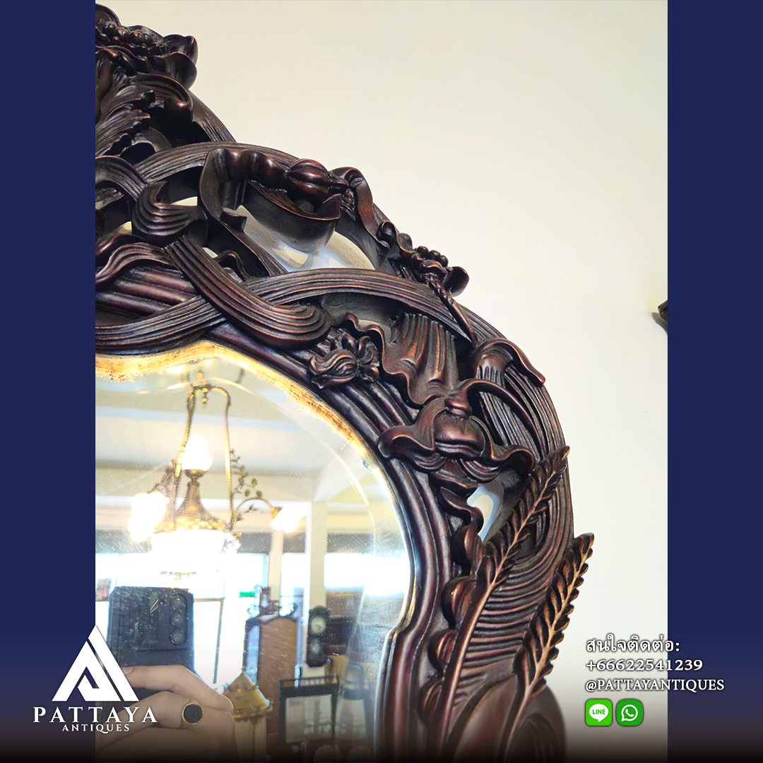 A pair of heavily carved mahogany Art Nouveau bevelled edged mirrors